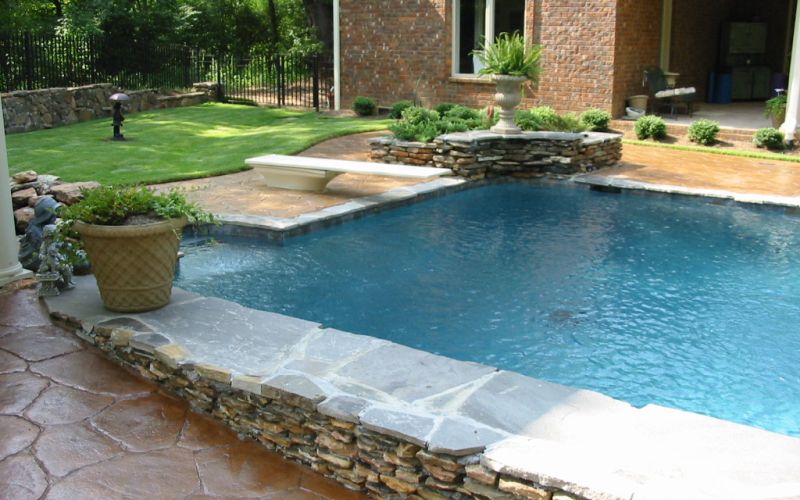 Pool with decorative concrete deck and natural stone accent.