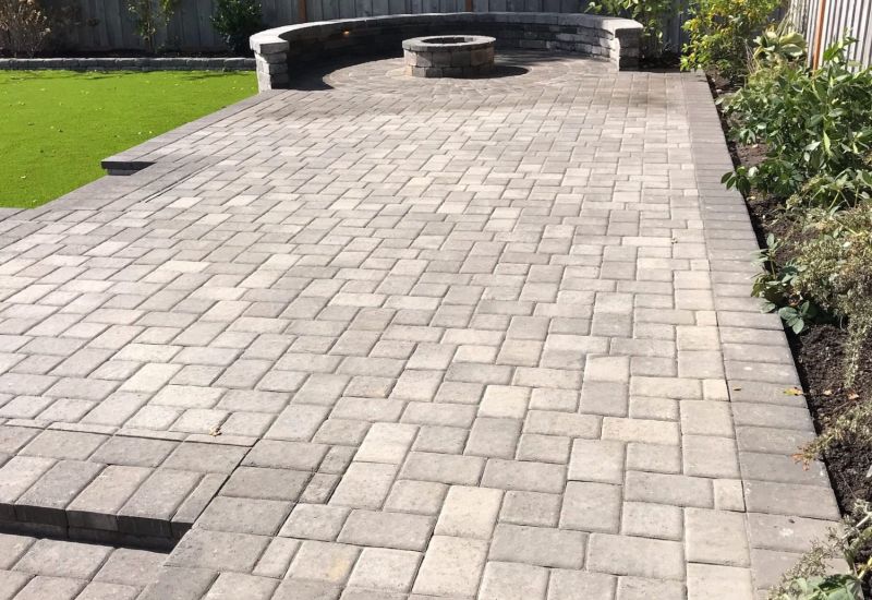 Custom stone patio installation with a natural gray brick pattern.